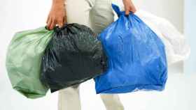 Una mujer baja la basura en distintas bolsas.