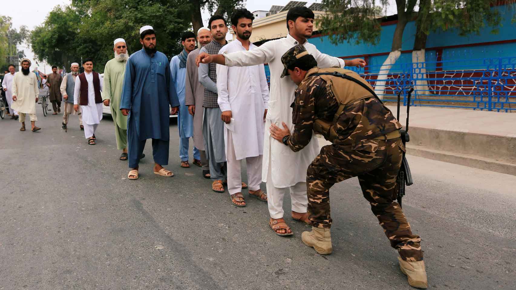 Un oficial de seguridad registra a los votantes antes de entrar en el colegio electoral de Jalalabad.