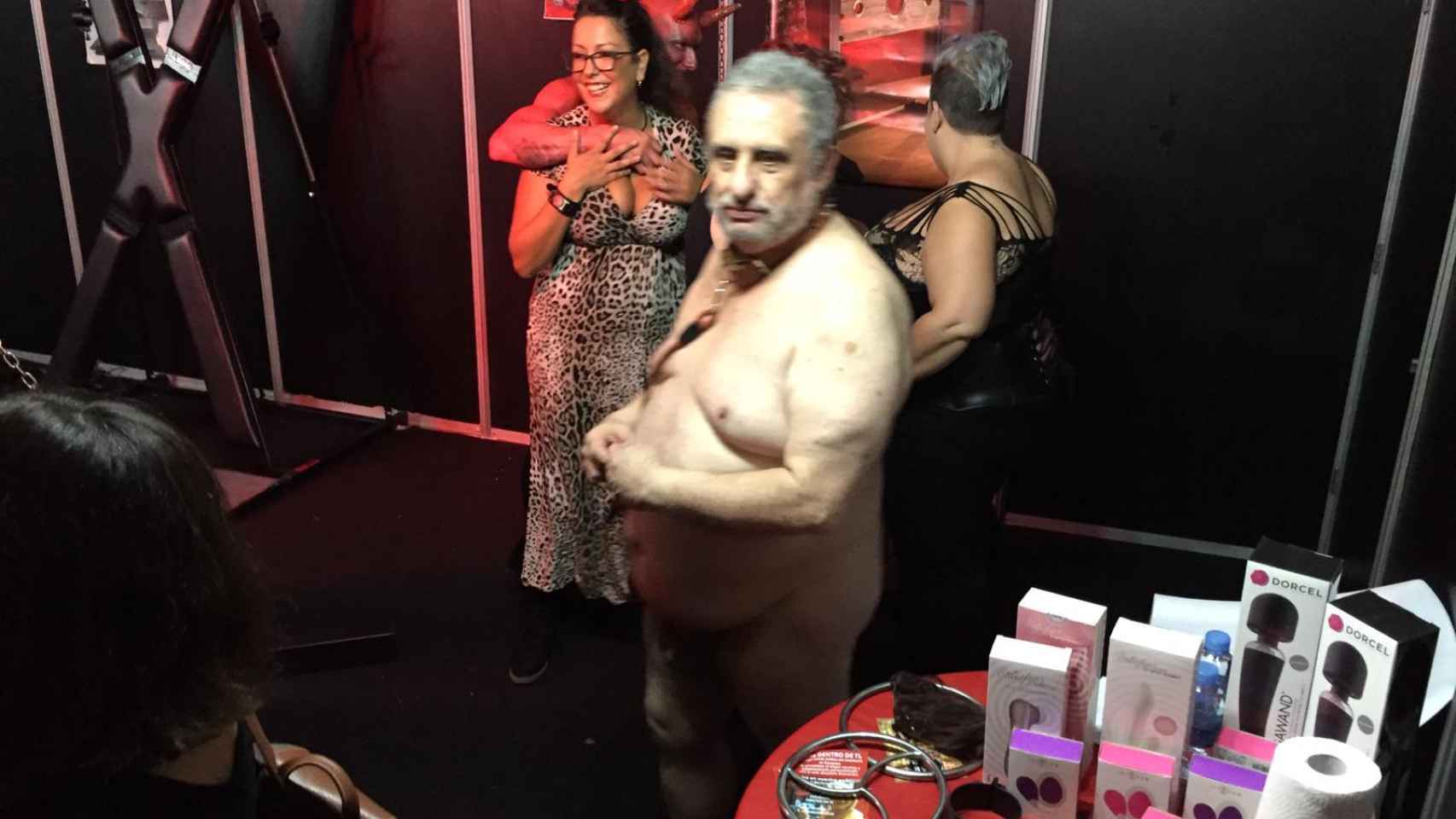 Hombre desnudo con collar de perro en el stand de BDSM