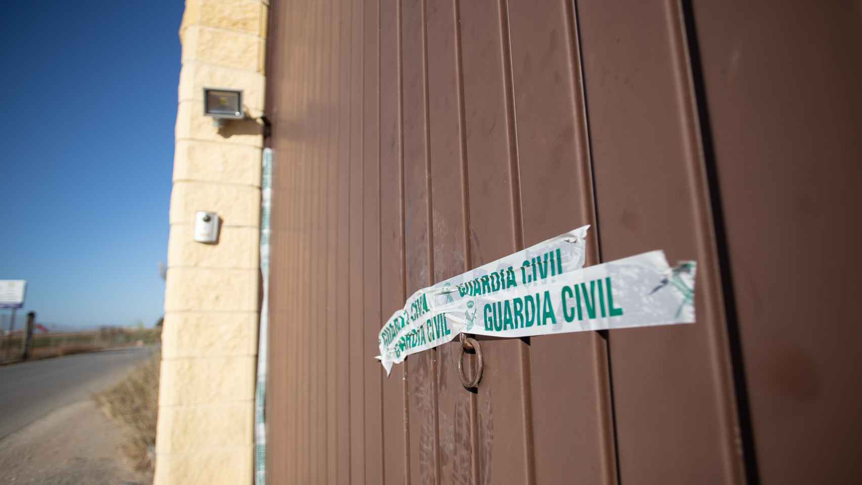 Portón de entrada a la vivienda en la que sucedieron los hechos, con un precinto de la Guardia Civil.