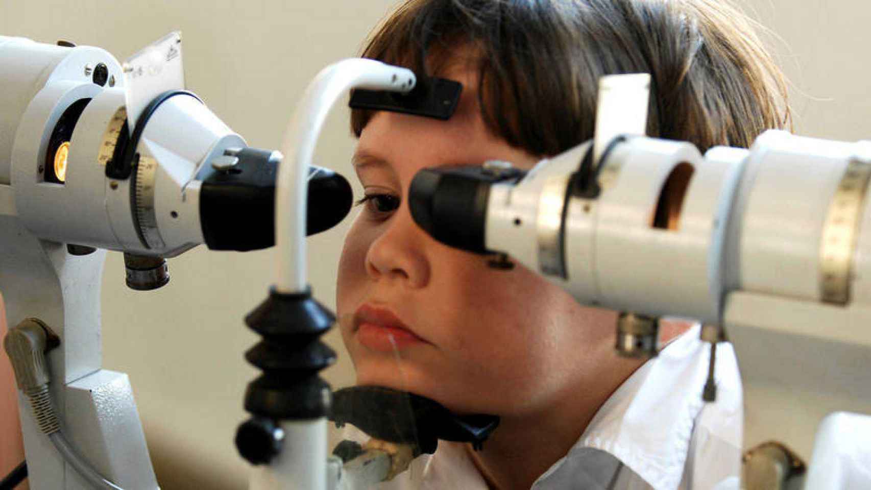 Imagen de archivo de un niño con miopía severa ejercitando la vista con la ayuda de equipo médico