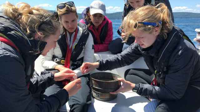 Un grupo de mujeres examina muestras de plástico extraídas del océano en una misión pasada de eXXpedition.