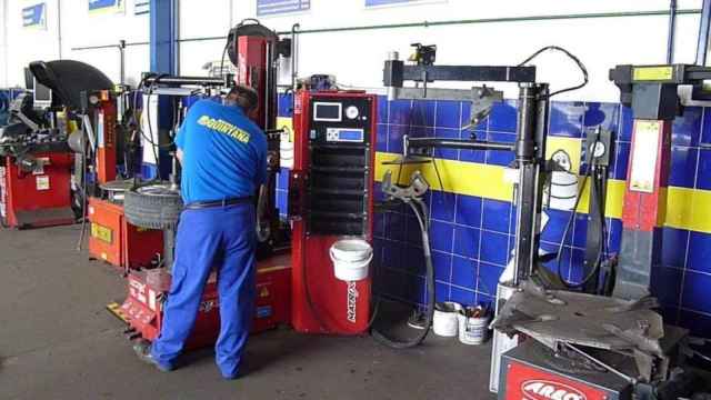Fotografía de un mecánico del taller de Mérida revisando ruedas, tomada en 2014.