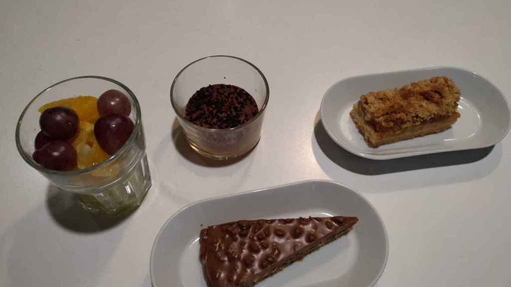 Postres variados: fruta, tarta de chocolate, tarta de manzana y de arándanos.