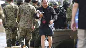 Un hombre con su perro en brazos es evacuado por los servicios de rescate en Motomiya.