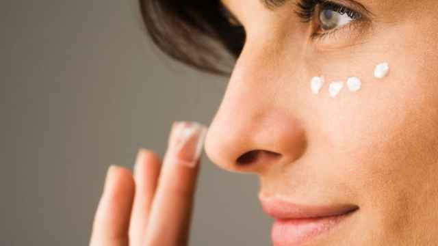 Una mujer se aplica crema en la cara.