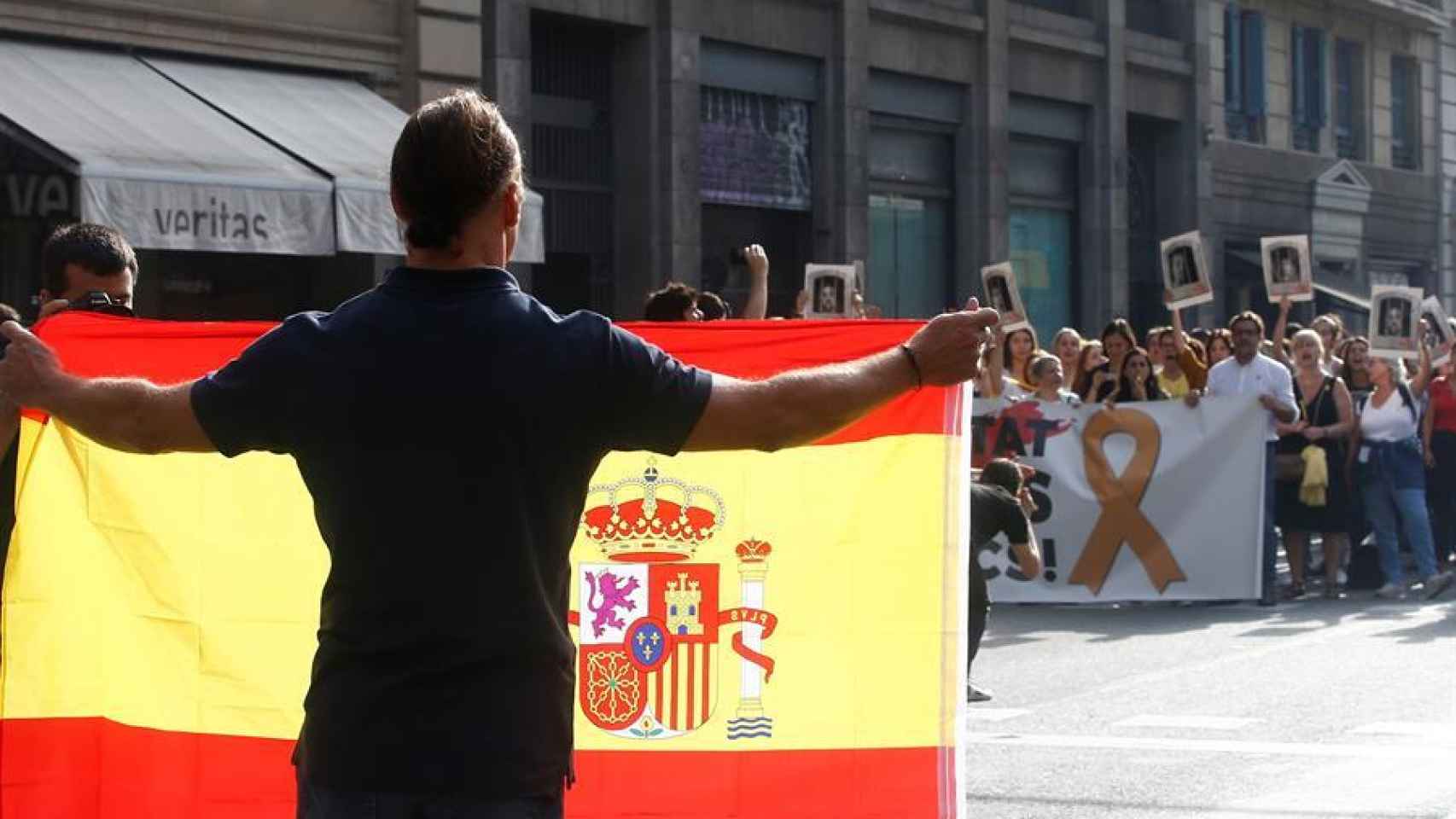 Un hombre con una bandera de España frente a una manifestación independentista tras conocerse la sentencia del 'procés'.