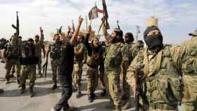 Combatientes rebeldes sirios respaldados por Turquía sostienen sus armas en Tel Abyad.