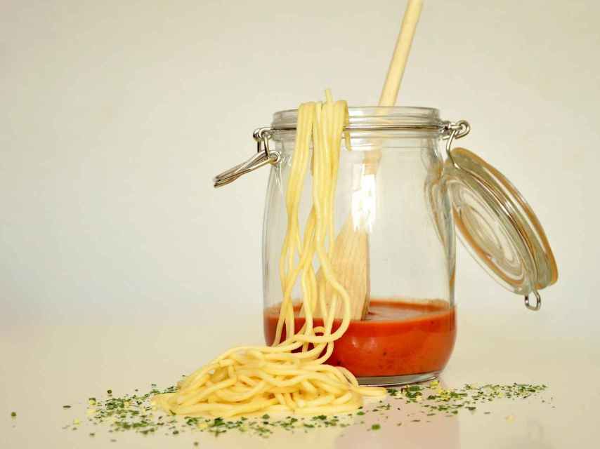Un tarro de cristal con salsa de tomate y unos espaguetis.