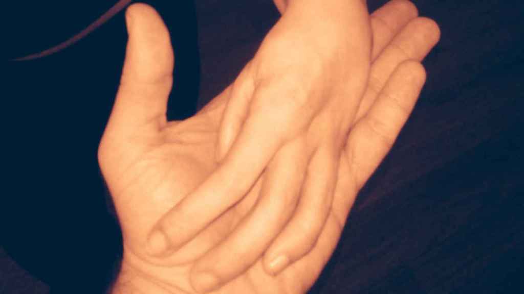 Detalle de la mano de un acompañante íntimo que oferta sus servicios en asistenciasexual.org acariciando la mano de un discapacitado físico.