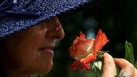 Una mujer huele una flor.