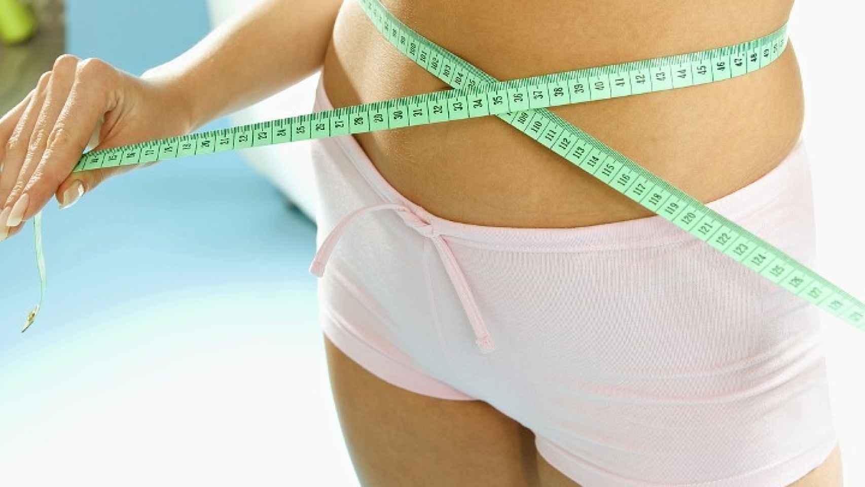 Una mujer se mide la cintura.