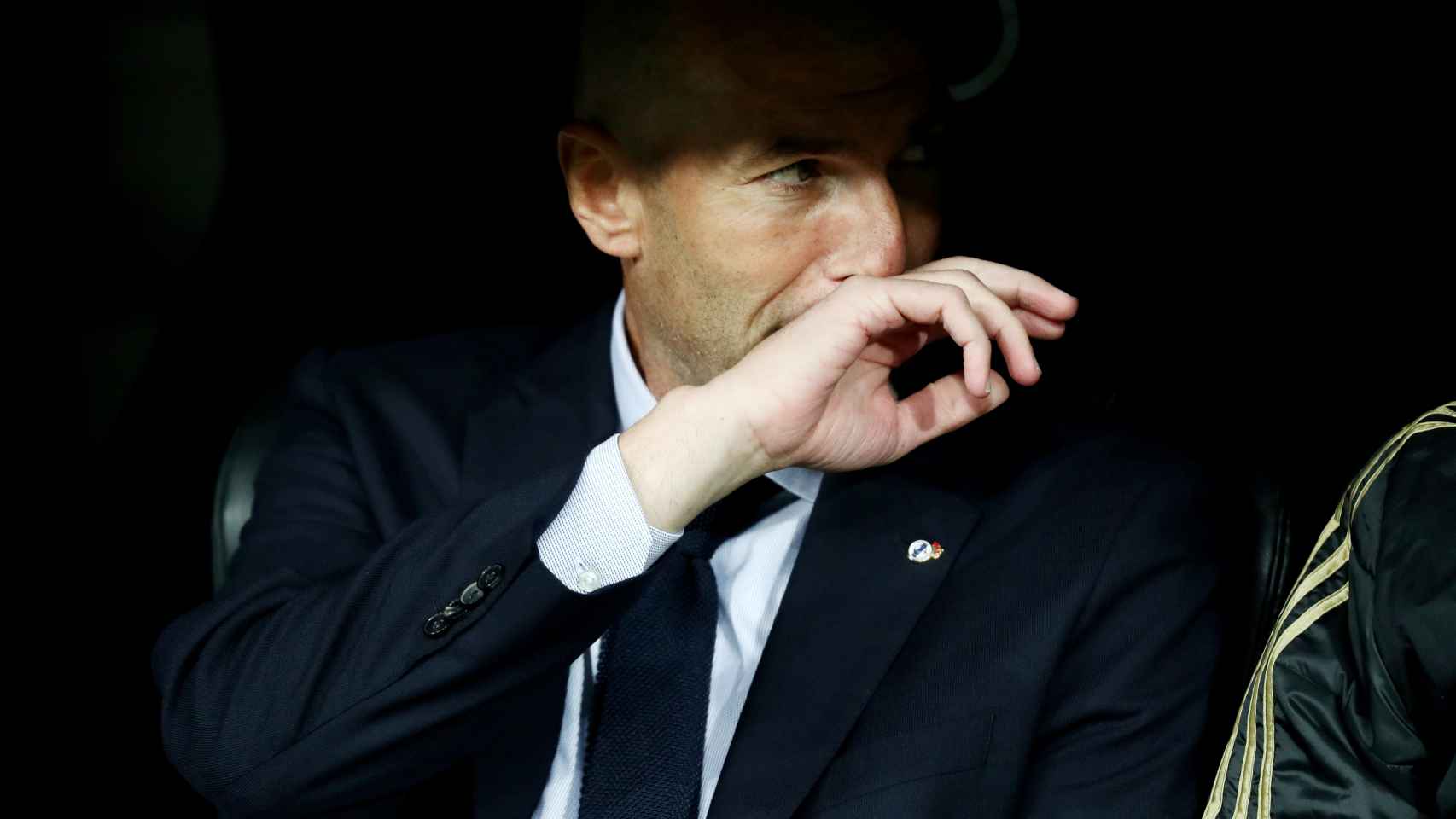 Zinedine Zidane habla con uno de sus ayudante en el banquillo del Santiago Bernabéu