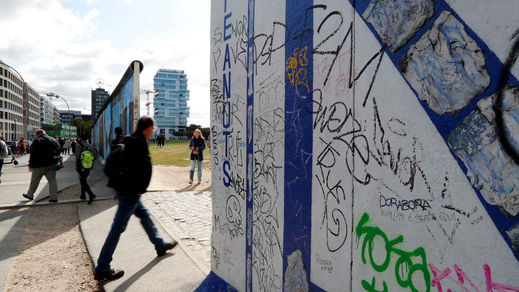 Varias personas caminan entre los restos del muro de Berlín.