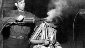 Un soldado estadounidense usando DDT para despiojar a una presa rescatada de un campo de concentración.