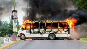 Un autobús ardiendo tras los enfrentamientos entre un cartel y la policía.