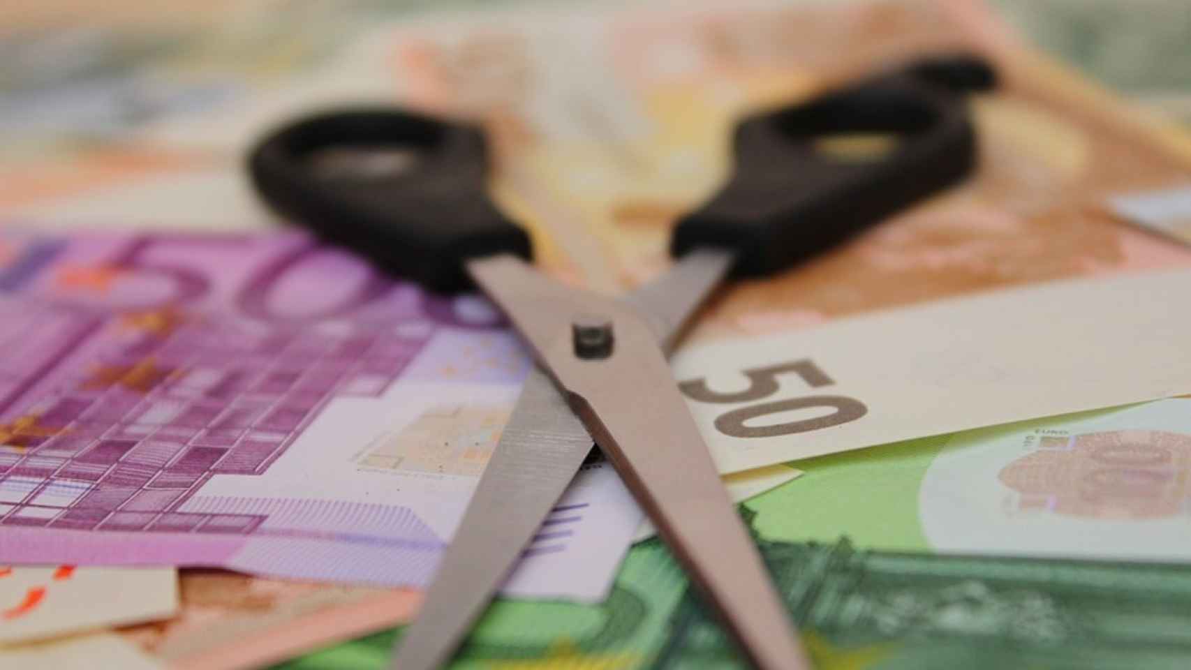 Unas tijeras sobre billetes de euro.