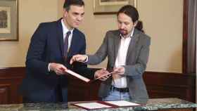 Pedro Sánchez y Pablo Iglesias intercambian documentos para firmar el preacuerdo de coalición.