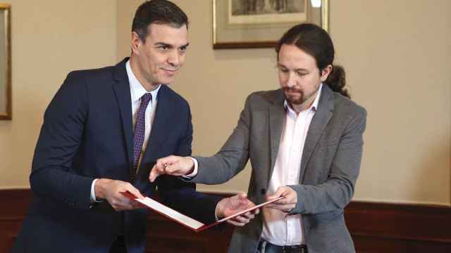 Pedro Sánchez y Pablo Iglesias intercambian documentos para firmar el preacuerdo de coalición.
