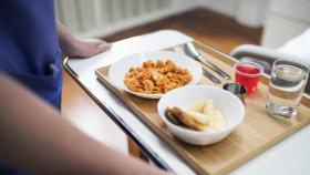 Un trabajador de un hospital lleva una bandeja con la comida de un paciente.