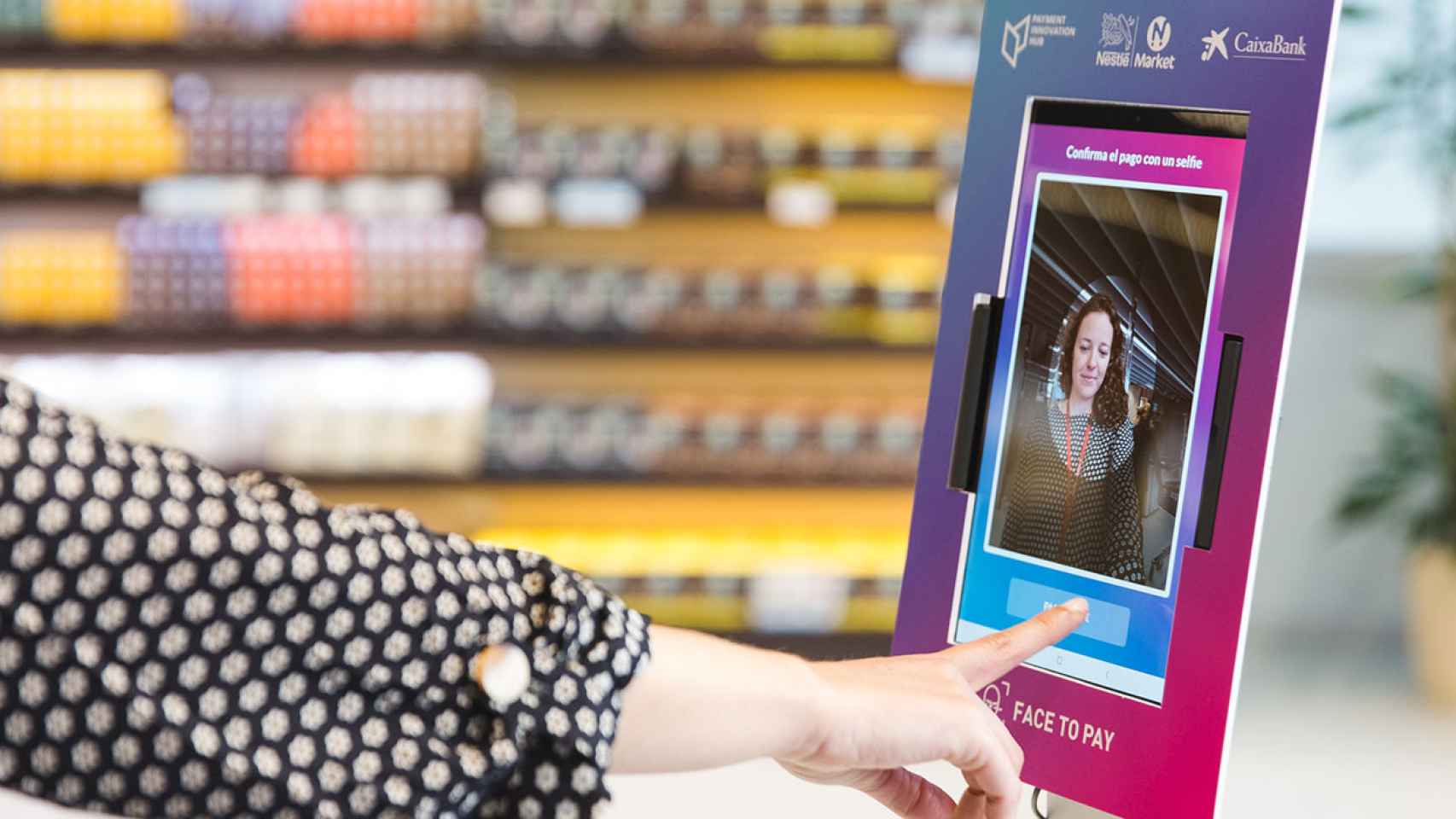 Un cliente pagando con la app Face to Pay de CaixaBank y Nestlé Market.
