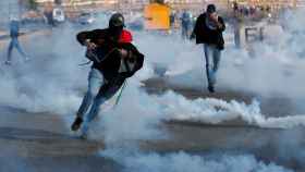 Manifestantes palestinos huyen del gas lacrimógeno durante una protesta en Cisjordania.