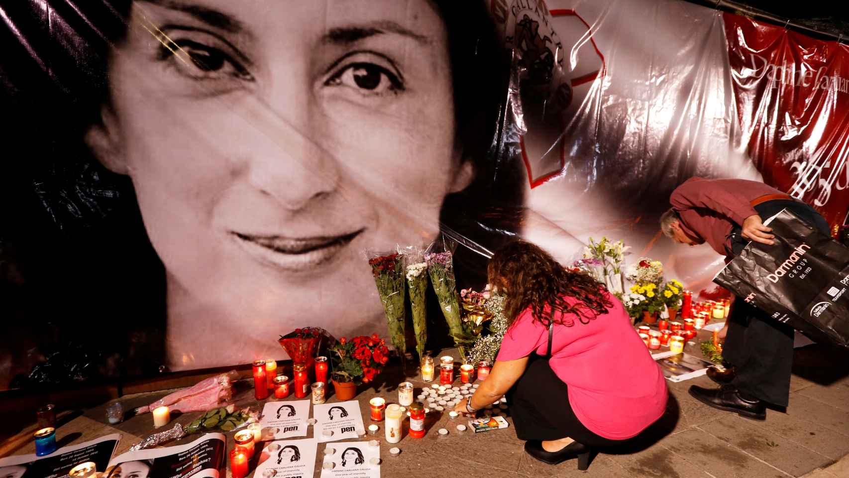Una mujer pone flores y velas en un monumento a la periodista anticorrupción Daphne Caruana Galizia.