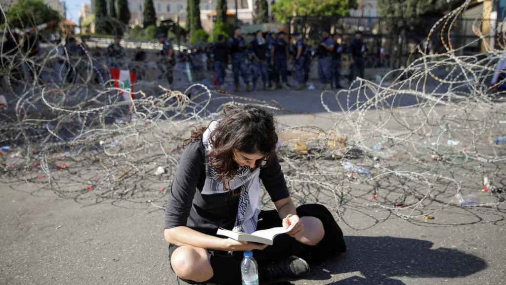 Una joven libanesa lee un libro en medio de una protesta contra el Gobierno.