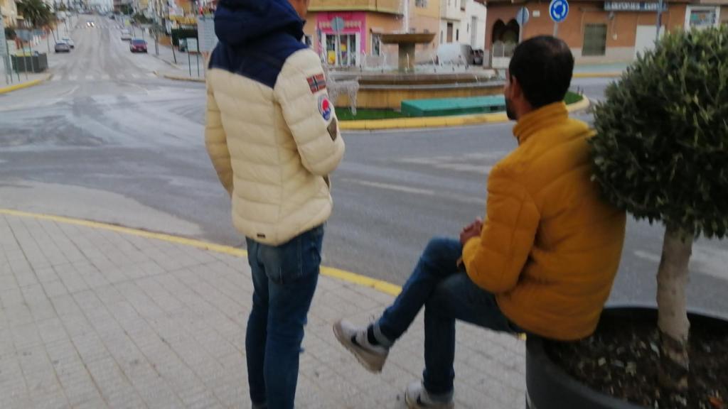 Jamal (sentado) y Amín, apostados en la rotonda donde pasan el día a la espera de quien los contrate aunque no tengan permiso de trabajo.