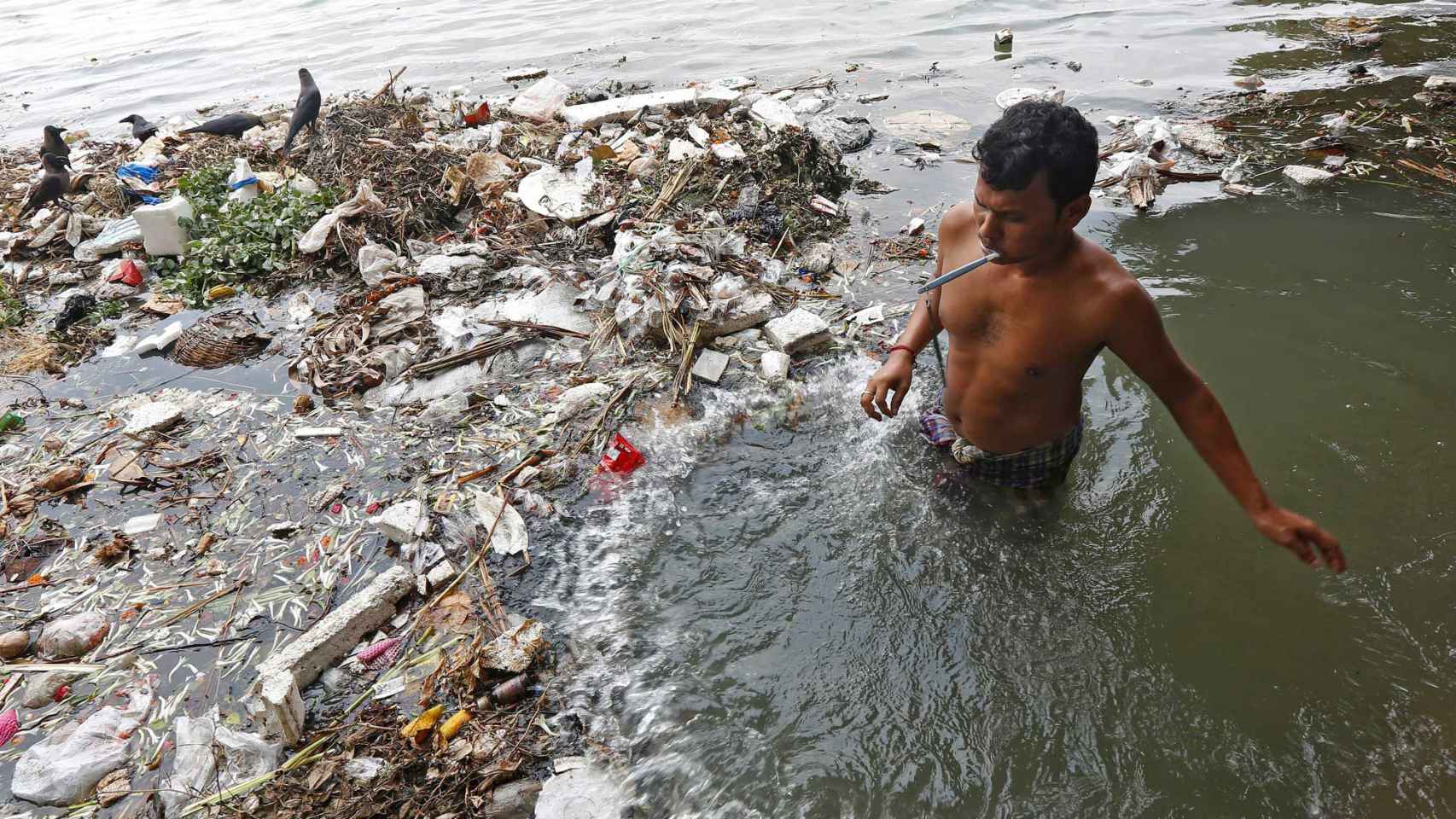 Un hombre se cepilla los dientes en el agua contaminada del río Ganges en Kolkata, India.