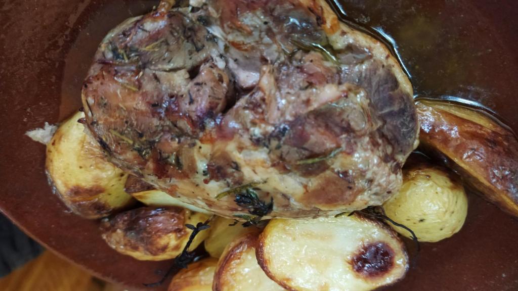 Vista del la pierna de cordero deshuesa y las patatas con mantequilla y romero, después de salir del horno.