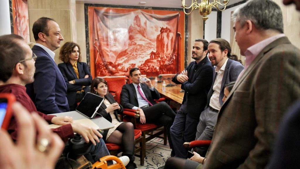 Los líderes del PSOE y Unidas Podemos, Pedro Sánchez y Pablo Iglesias, charlan con sus equipos tras la presentación del programa de su gobierno de coalición.