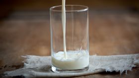 Una jarra de leche con un vaso a medio llenar.