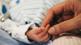 Un bebé recién nacido sujeta la mano de su madre.