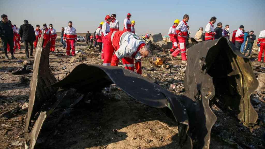 Trabajadores de la Media Luna Roja revisan los escombros del avión.