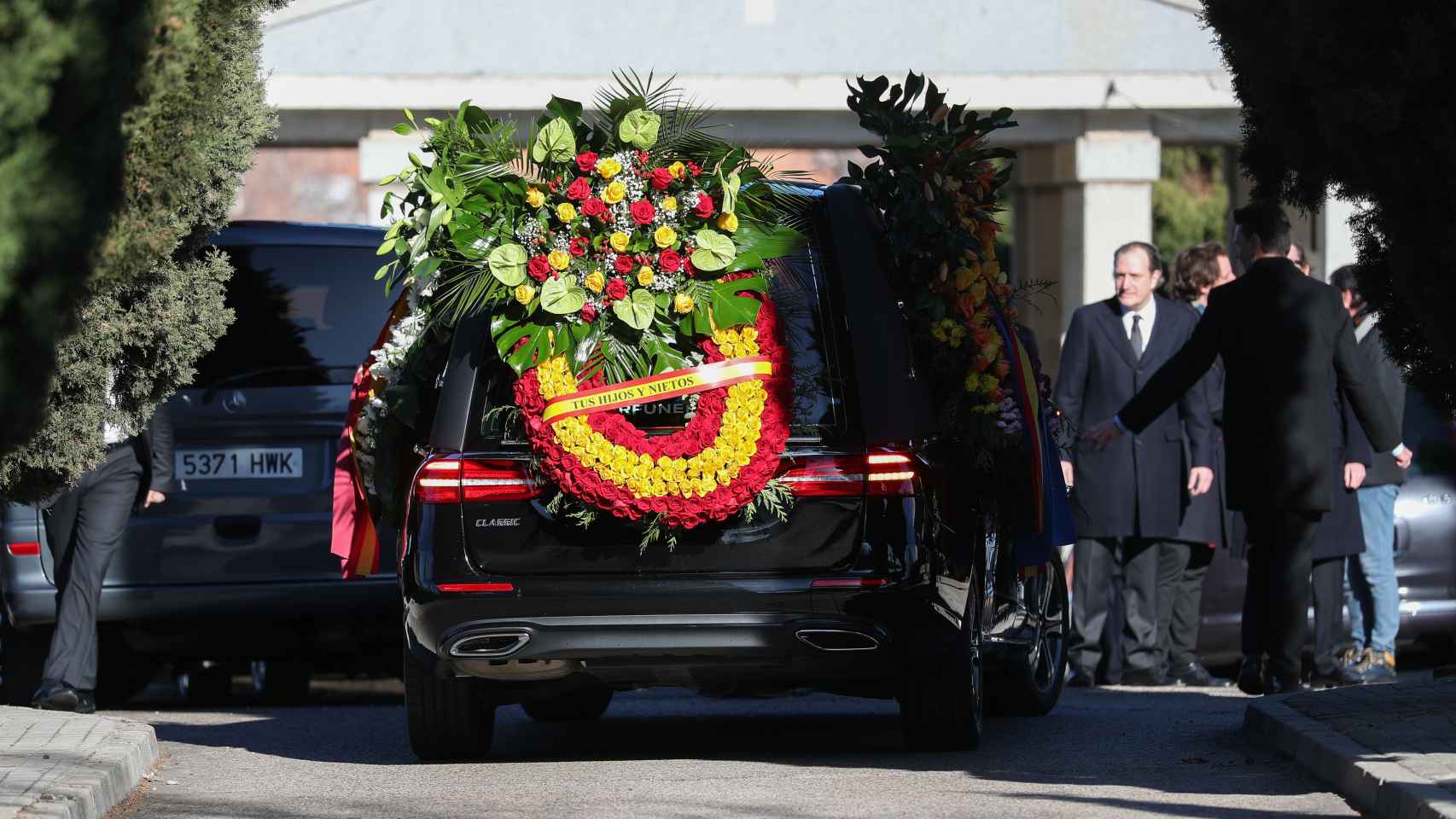 El coche fúnebre con una gran corona de flores con los colores de la bandera de España.