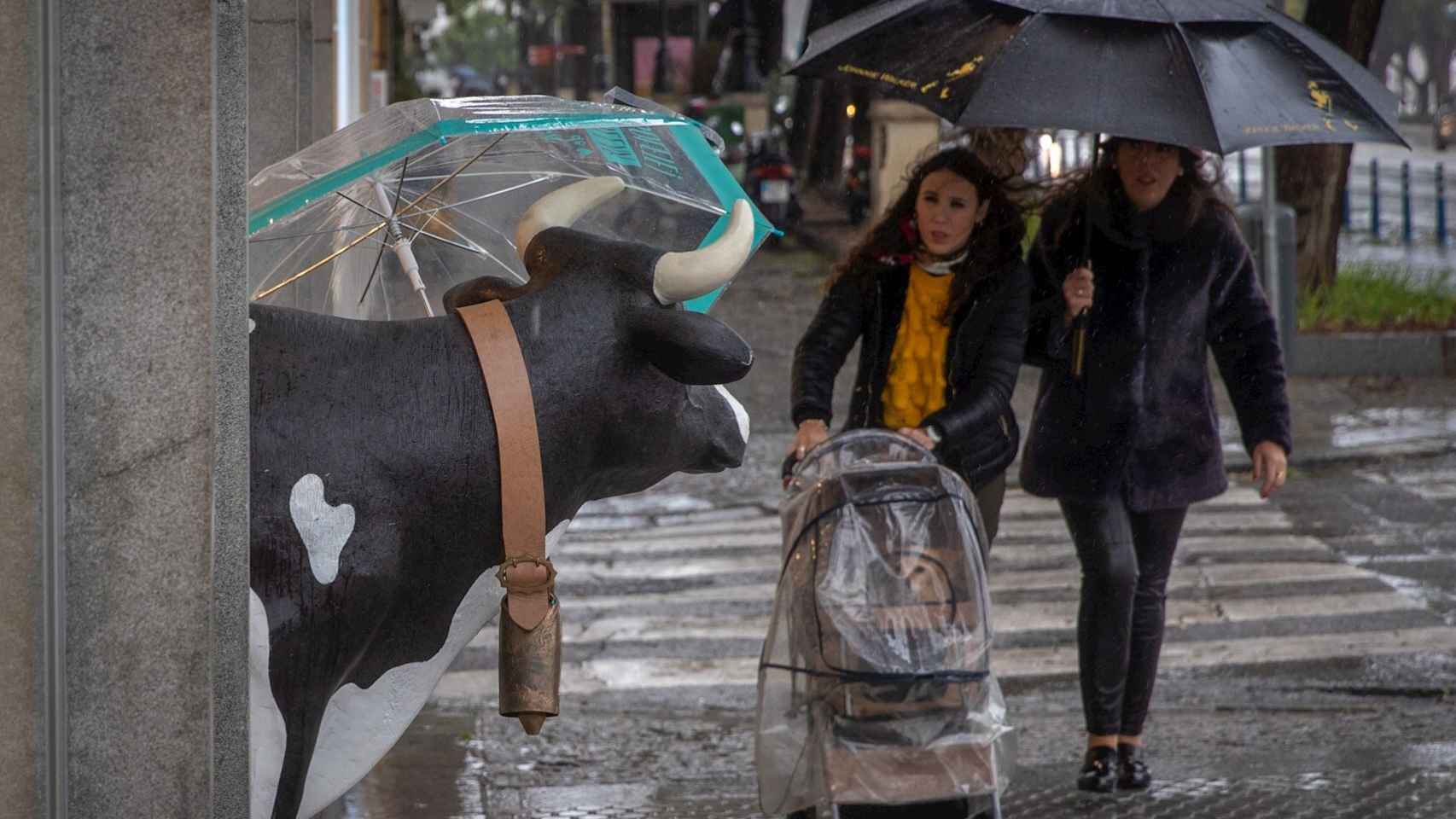 Dos mujeres se protegen de la lluvia. EFE/Julio Muñoz.