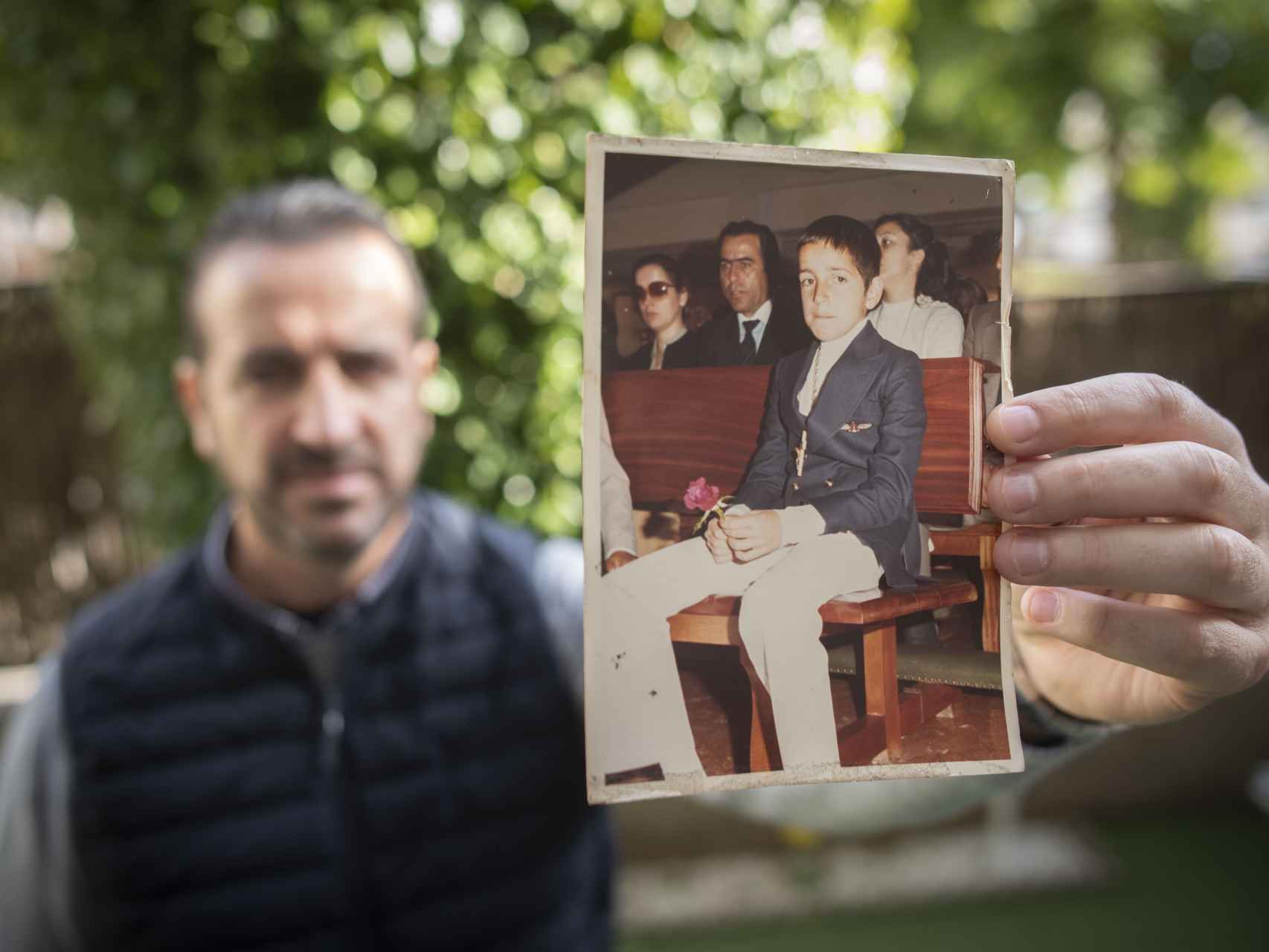 Carlos Aguilar sostiene una foto del día de su comunión. En la imagen, sentado delante de sus padres, Juan Galán e Isabel Aguilar.