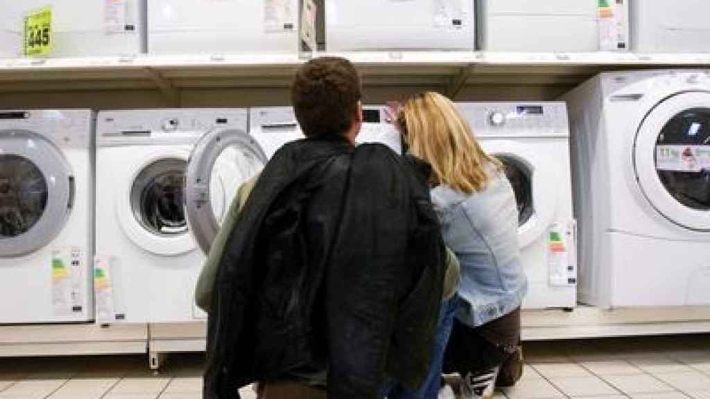 Una pareja, observando las lavadoras de un supermercado.