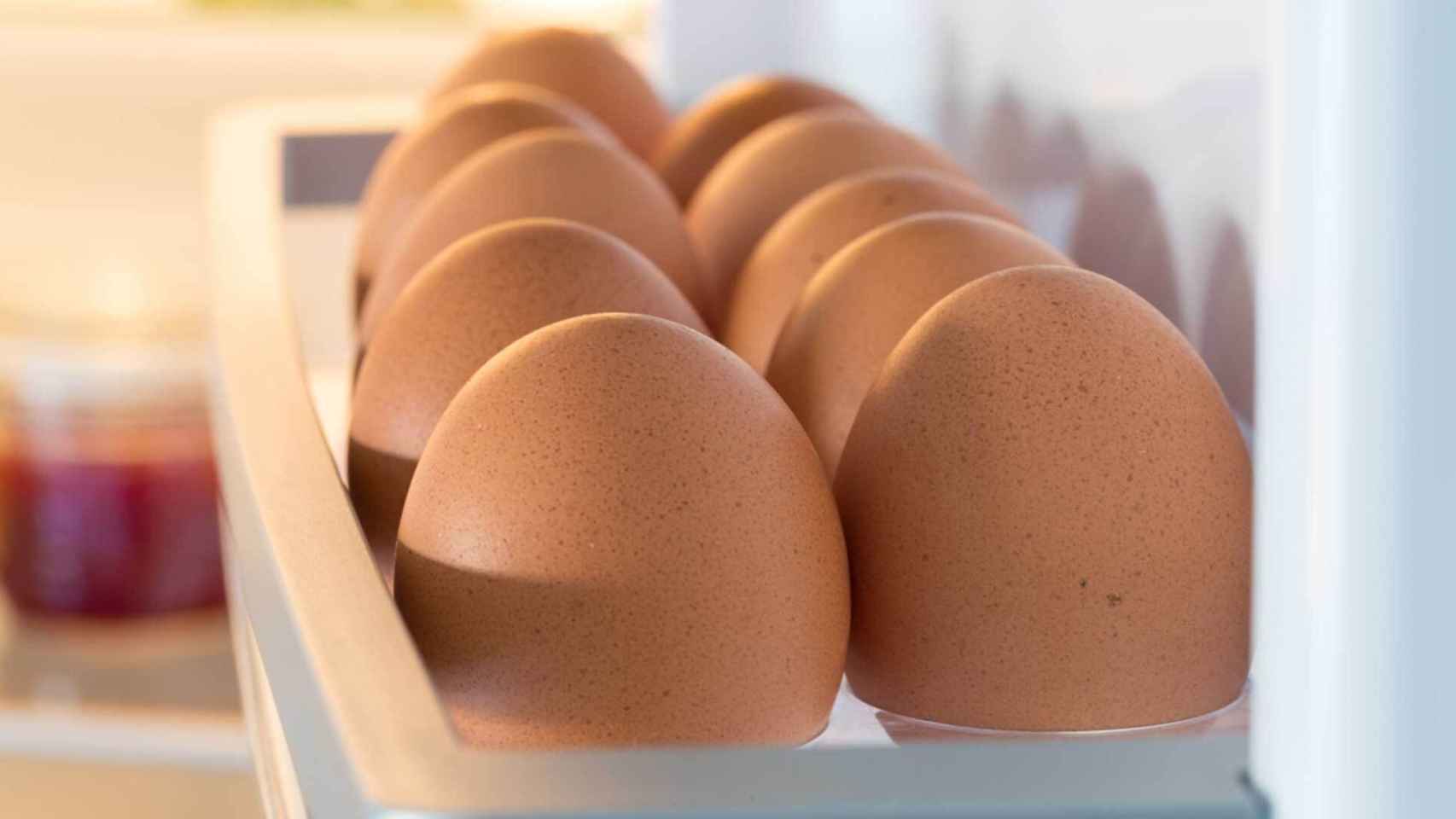Unos huevos colocados en la huevera de la puerta del frigo.