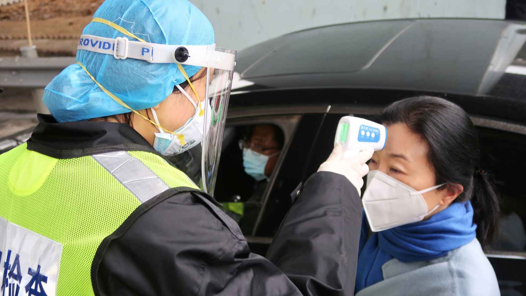 Un guardia de seguridad le toma la temperatura a una señora en Xianning (China), para comprobar que no tiene fiebre.
