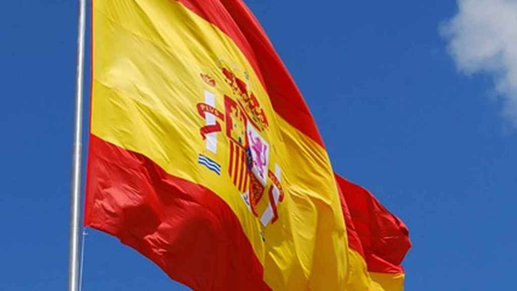 La bandera de España ondeando sobre un cielo azul intenso.