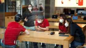 Jóvenes con mascarillas en una Apple Store en Beijing.