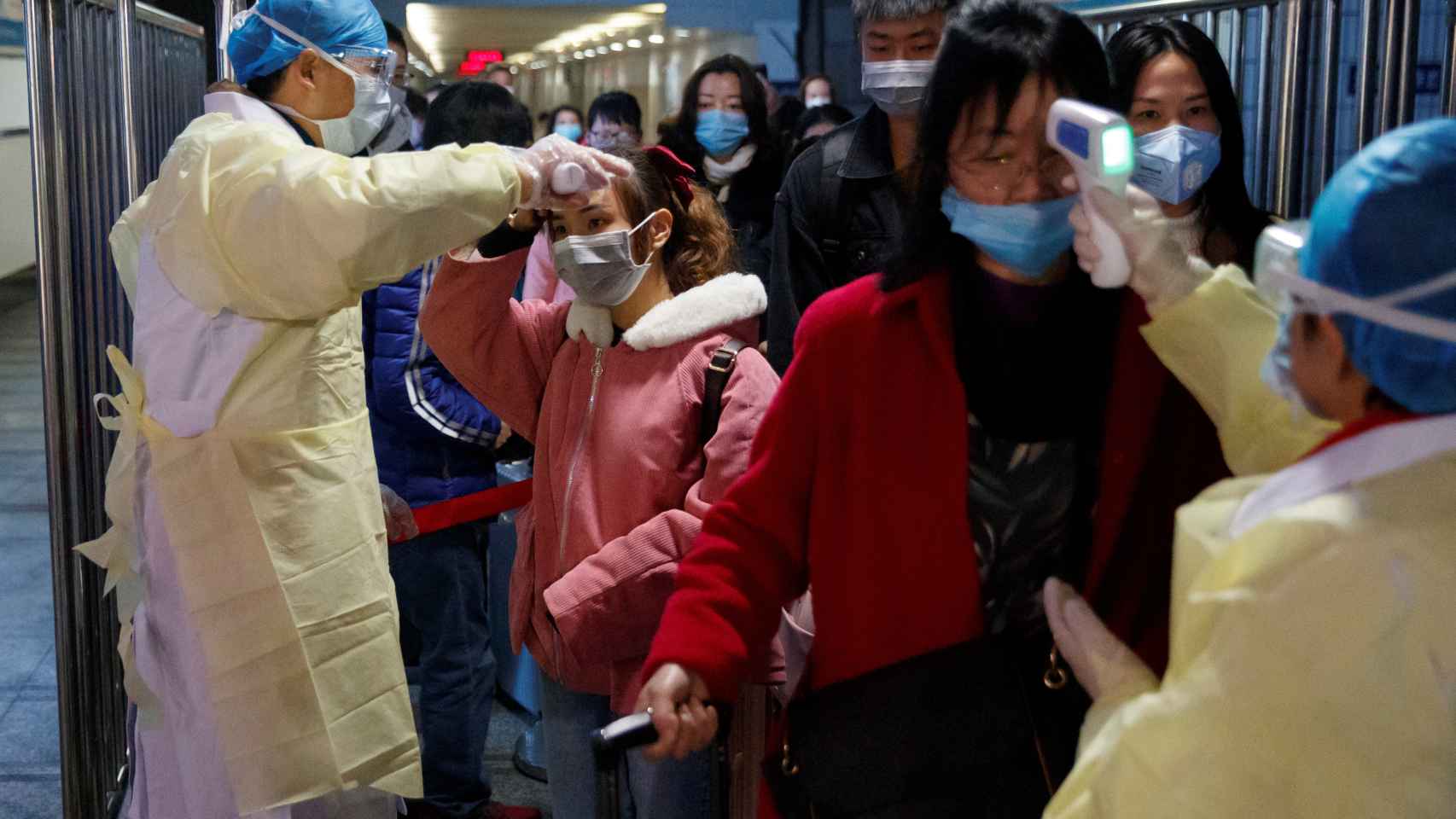 Personal médico toma la temperatura a pasajeros en una estación de tren en Jiujiang, China.