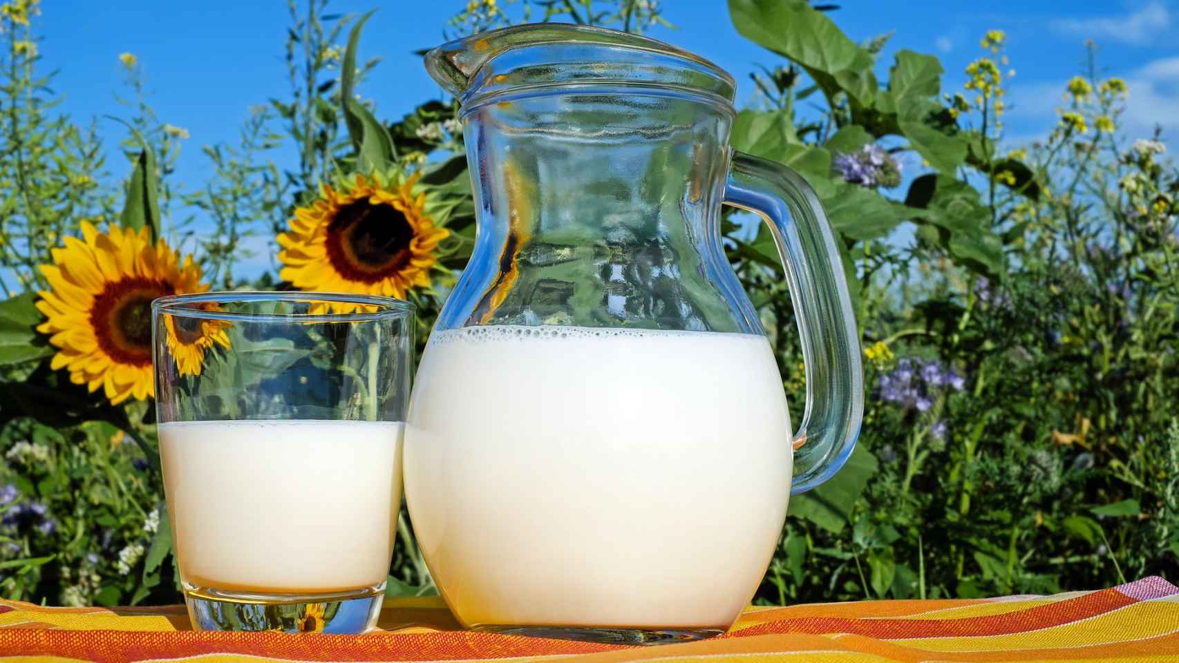 Un vaso de leche junto a una jarra.