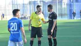 El árbitro dialogando con un jugador del Ceuta durante el partido