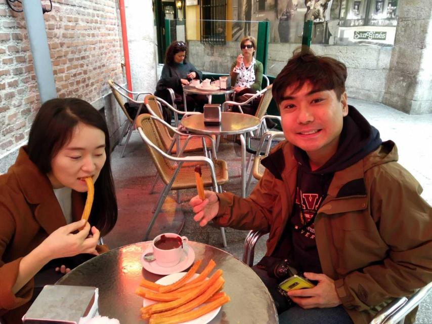 Una pareja de Corea del Sur se toma un chocolate con churros en San Ginés.