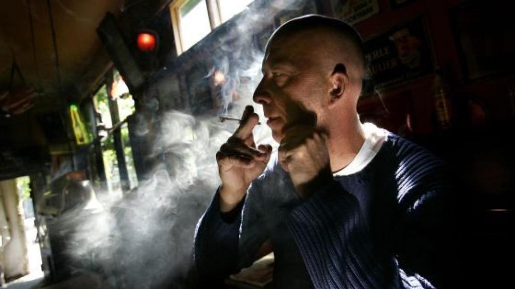 Un hombre fuma un porro en un coffeeshop.