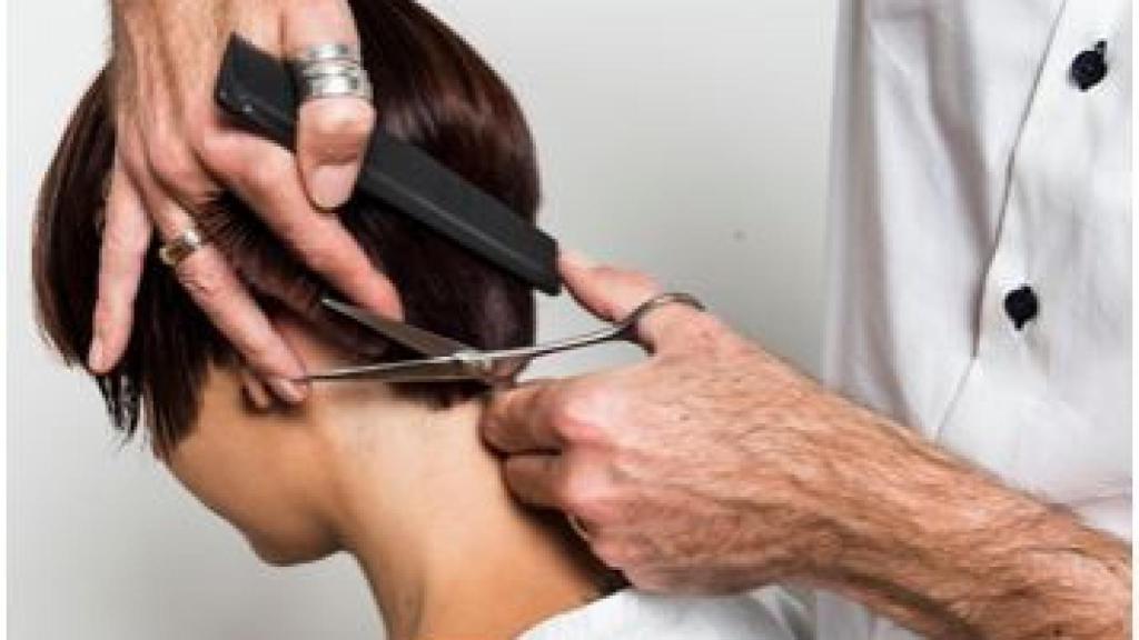 Un peluquero cortando el pelo de una mujer.
