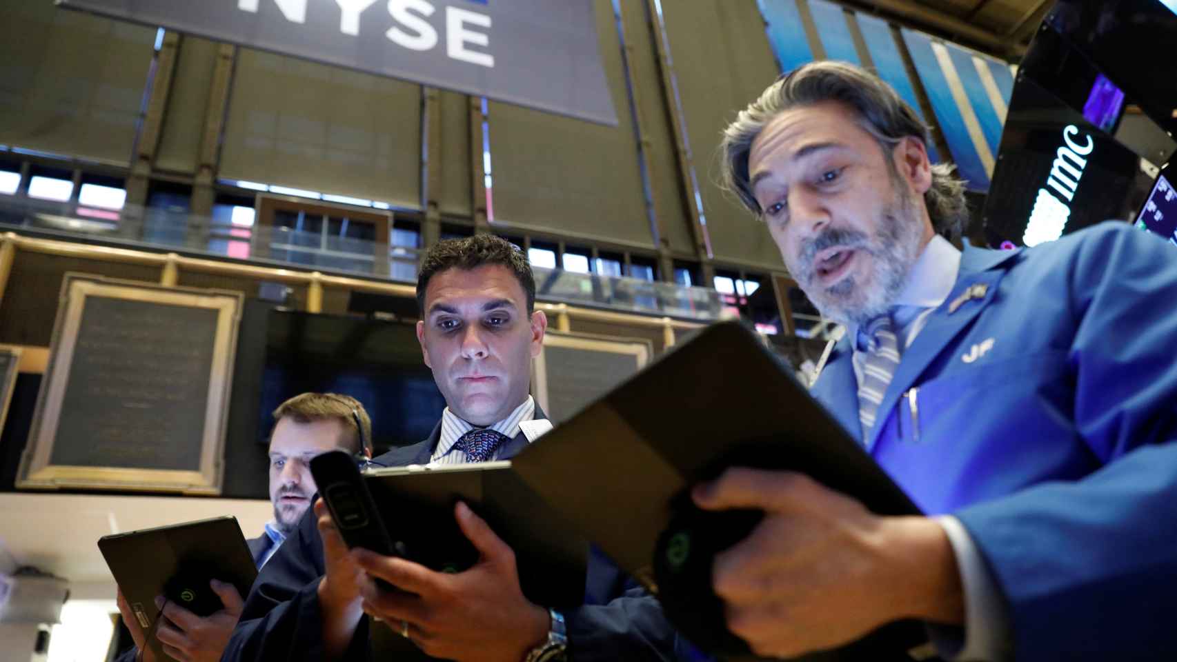 Tres operadores con gesto de asombro en la Bolsa de Nueva York.
